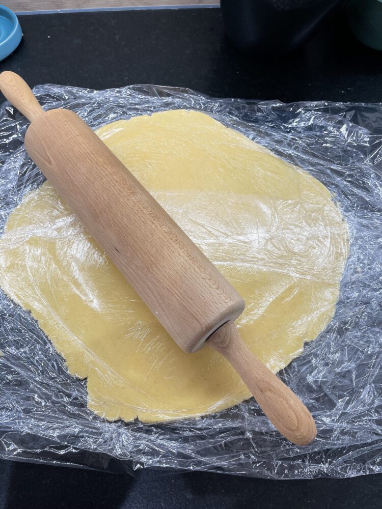 Teig wird vorsichtig auf Frischhaltefolie ausgerollt